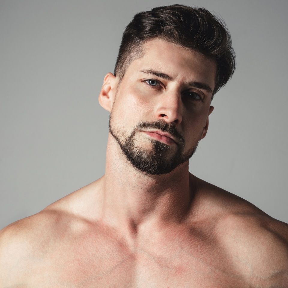 Portrait of a naked handsome young man posing over gray background. Perfect body and skin. Studio shot.