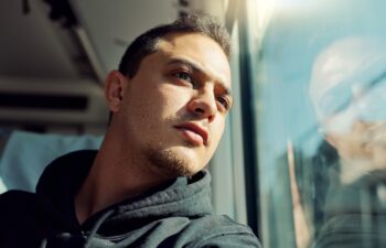 Thinking, sad and young man on train with mental health problem or loneliness on trip or journey. Depression, upset and male person from Canada on public transportation for vacation or holiday.