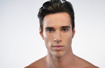 Portrait of a beautiful smiling man showing white teeth looking into camera or making faces of doubt or blunders with perfect skin and combed hair.